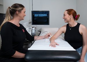 Sonographer does an ultrasound on a woman's elbow at Sunshine Coast Radiology
