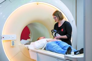 MRI technician caring for a patient as they go into an MRI scan