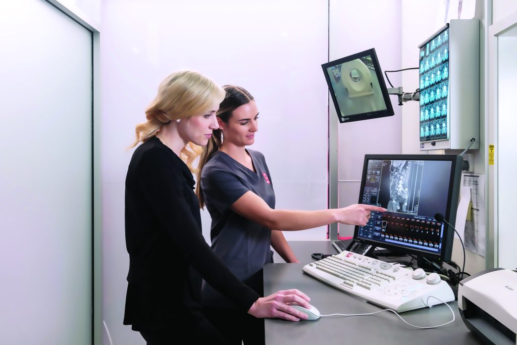 MRI technician discussing MRI scan with radiologist pointing at image on screen