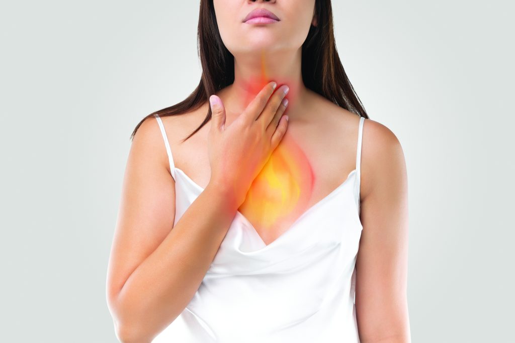 A woman touching her throat with warm red and orange colours showing the reflux or GORD that she's suffering from