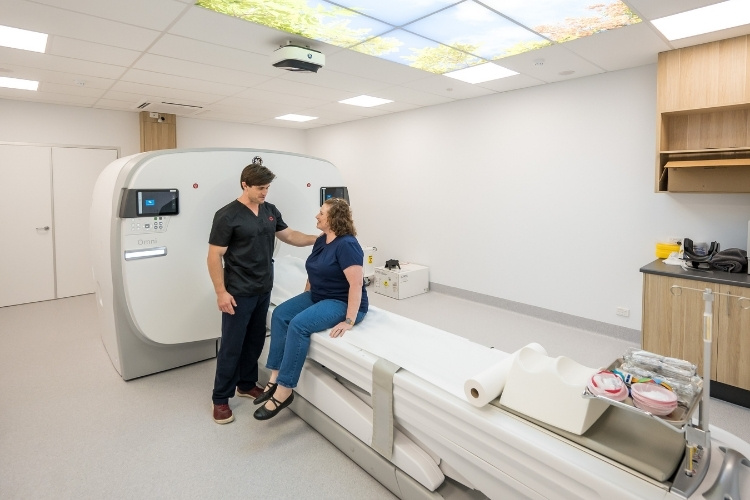 Nuclear Medicine Technologist informs female patient of next steps in a PET CT scan.