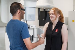 Radiographer positions male patient for OPG dental imaging.