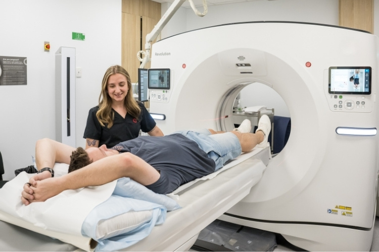Radiographer prepares male patient before he enters CT scan.